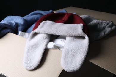 Different used clothes in box on dark background, closeup