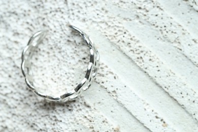 Photo of Beautiful silver ring on stone surface, top view. Space for text