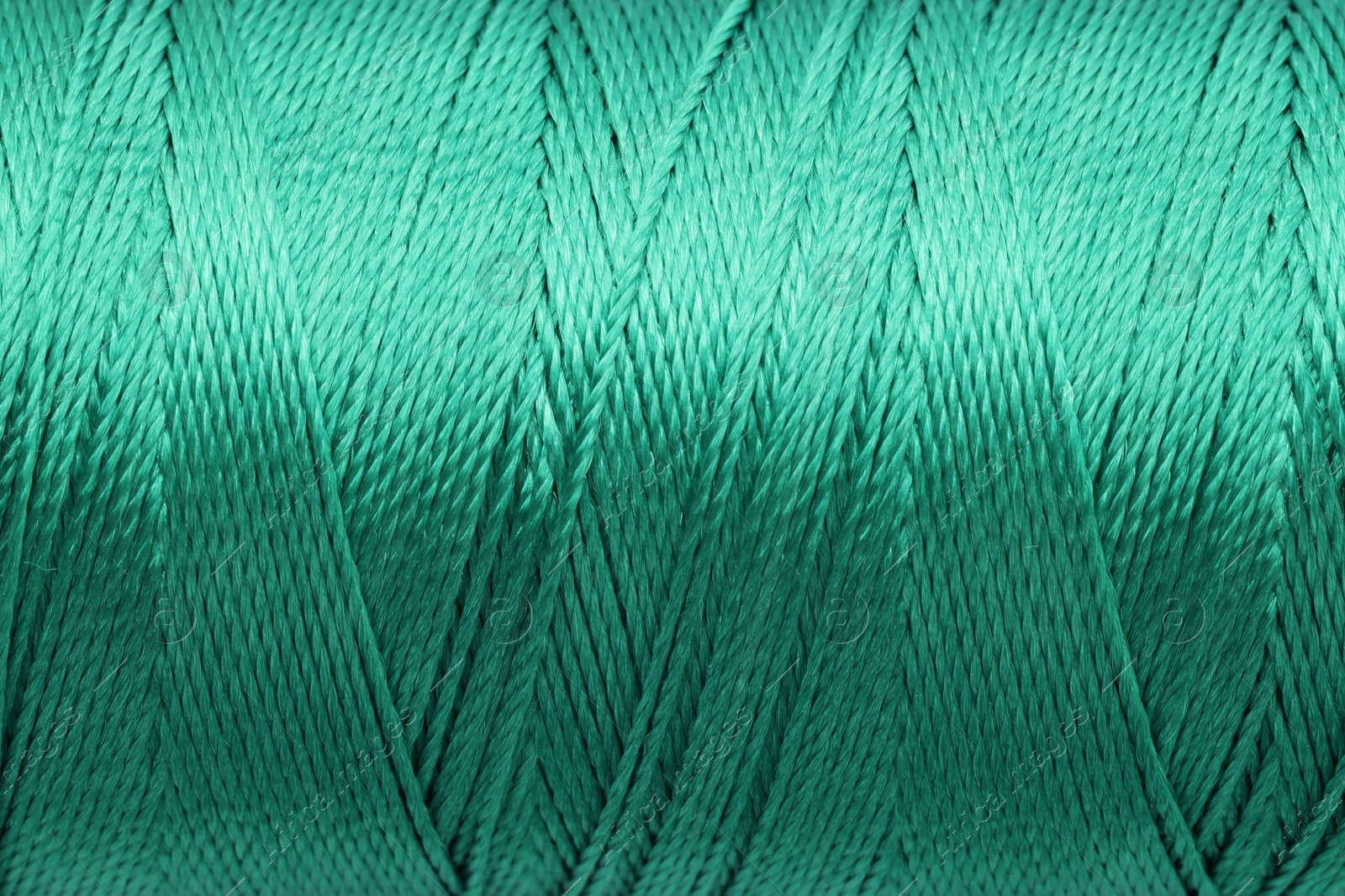 Photo of Beautiful green sewing thread as background, closeup