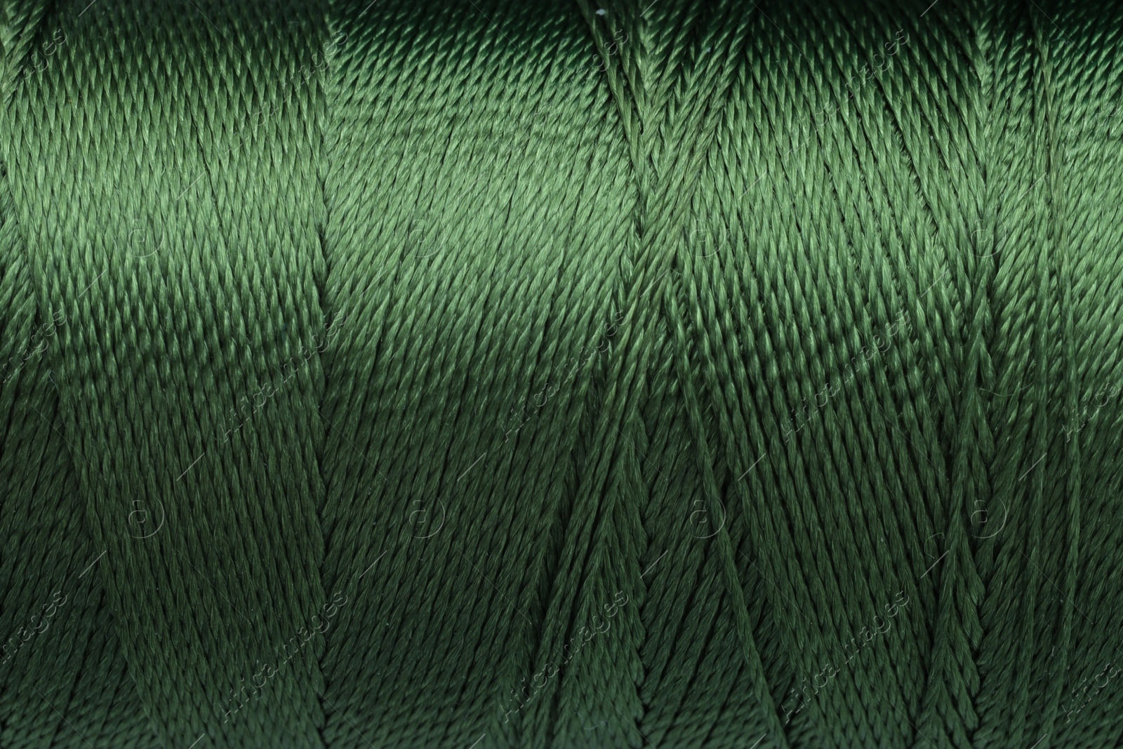 Photo of Beautiful khaki sewing thread as background, closeup