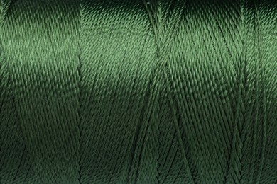 Photo of Beautiful khaki sewing thread as background, closeup