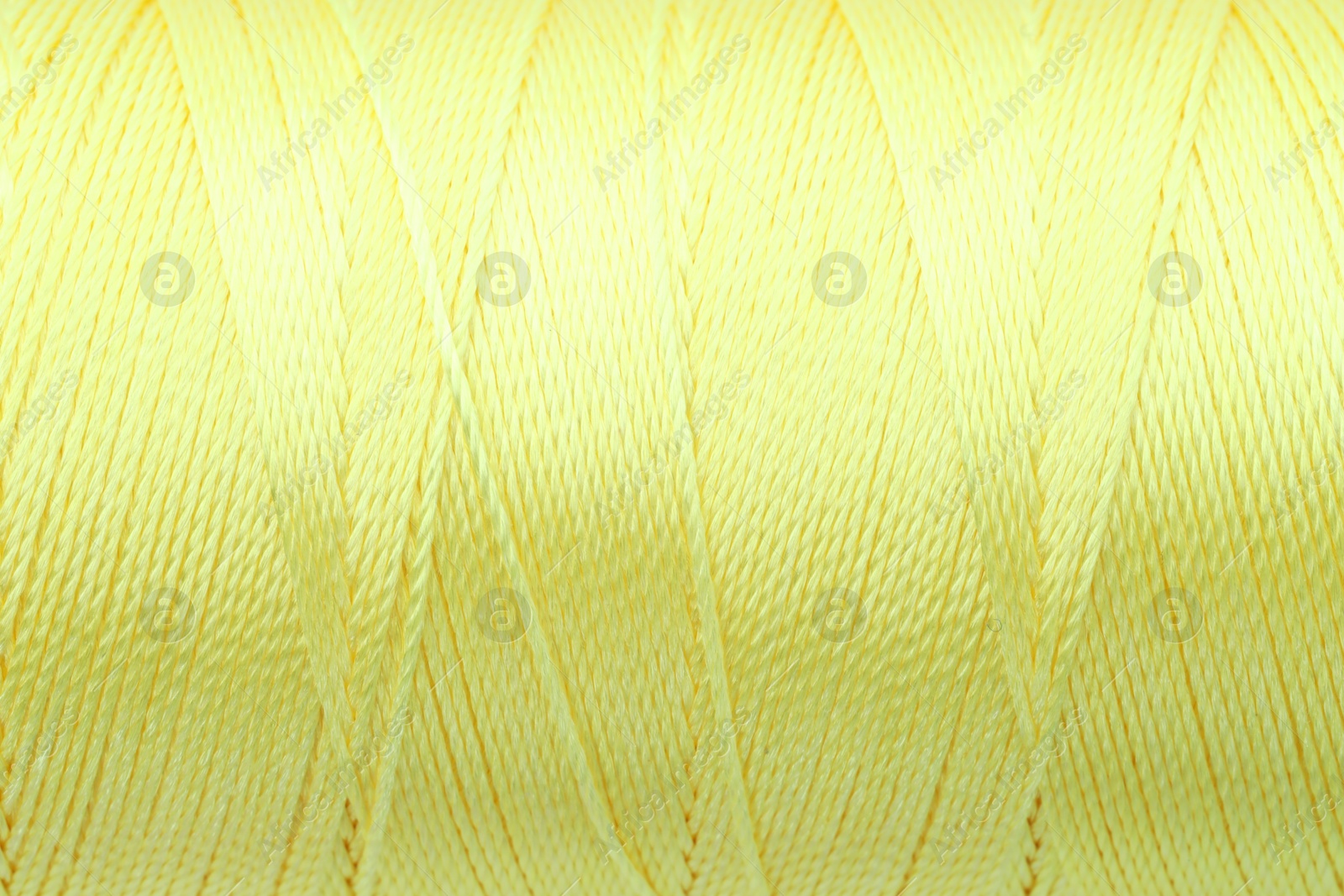 Photo of Beautiful yellow sewing thread as background, closeup