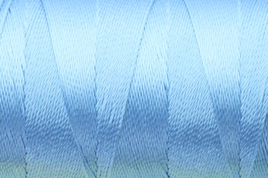 Photo of Beautiful light blue sewing thread as background, closeup