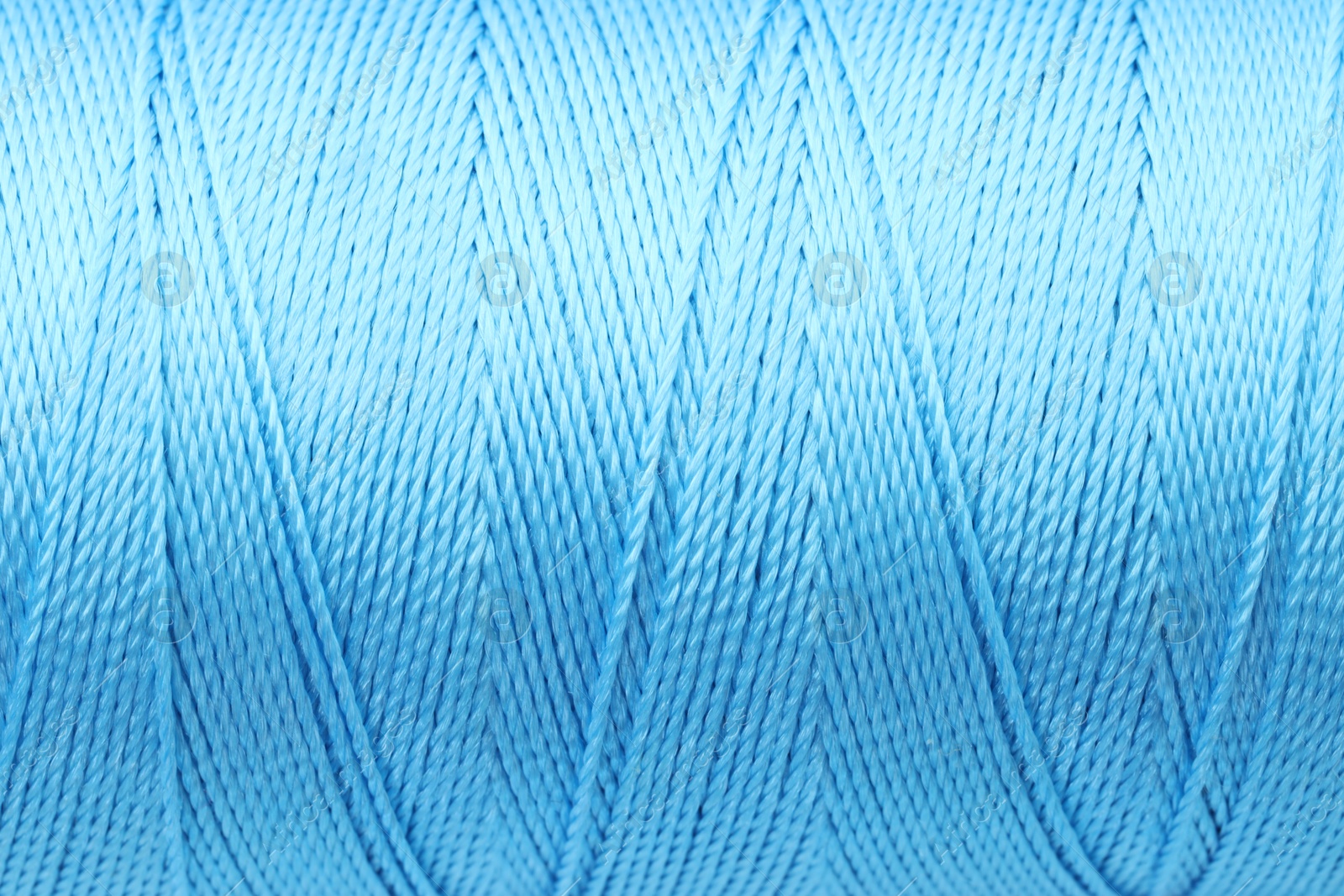 Photo of Beautiful light blue sewing thread as background, closeup