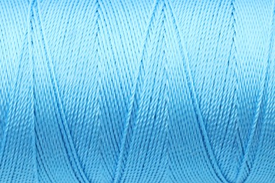 Photo of Beautiful light blue sewing thread as background, closeup