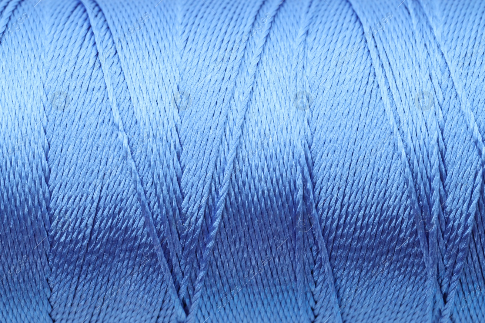 Photo of Beautiful blue sewing thread as background, closeup