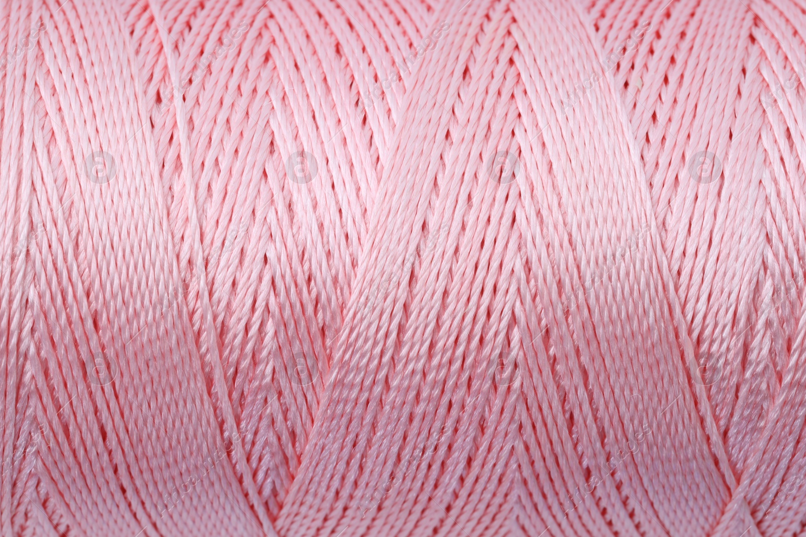 Photo of Beautiful light pink sewing thread as background, closeup