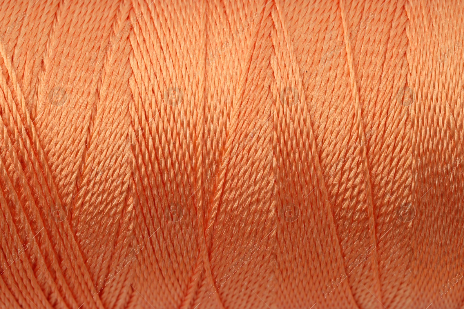 Photo of Beautiful orange sewing thread as background, closeup