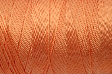 Photo of Beautiful orange sewing thread as background, closeup