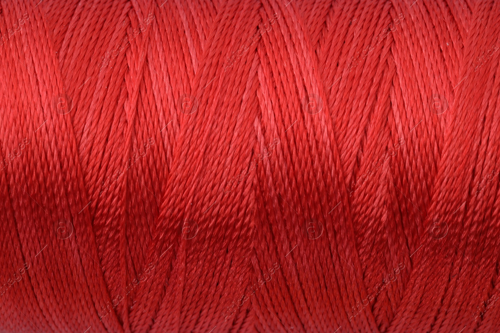 Photo of Beautiful red sewing thread as background, closeup