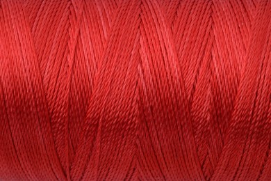 Photo of Beautiful red sewing thread as background, closeup