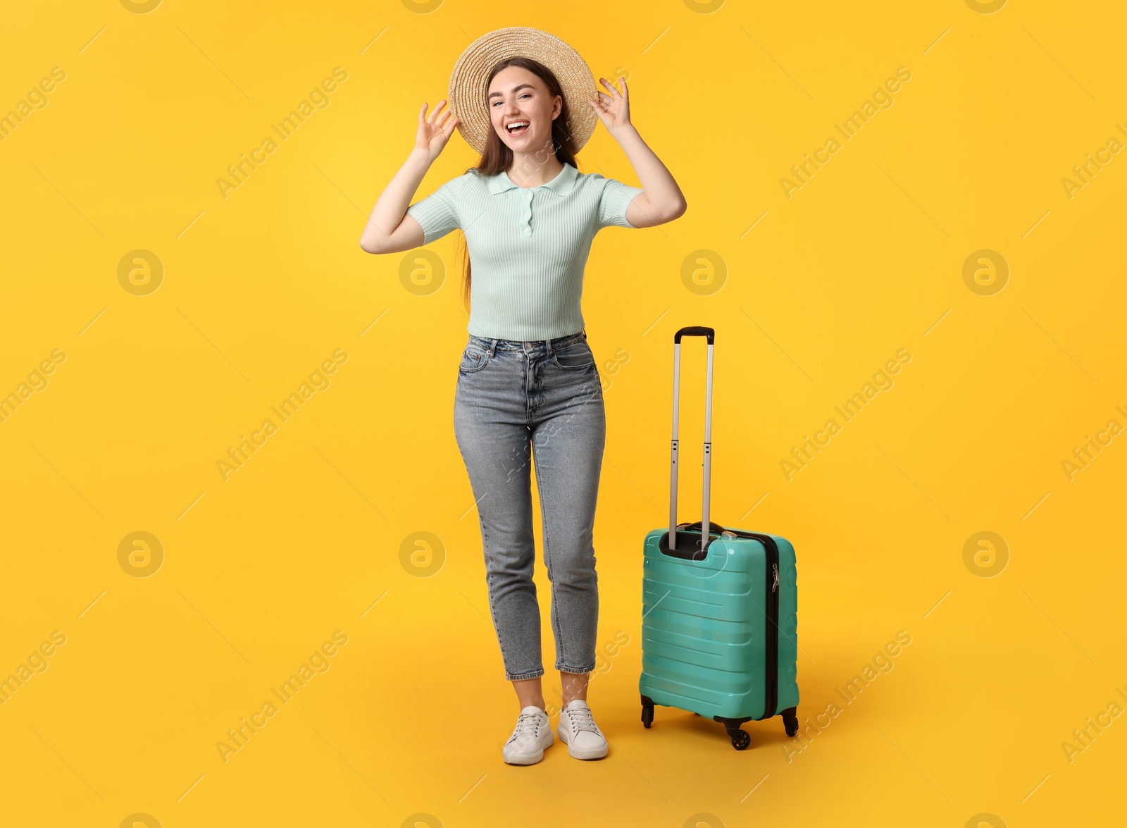 Photo of Woman in straw hat with suitcase on orange background