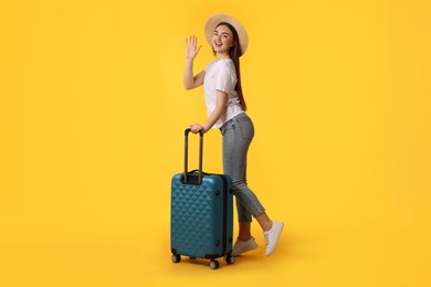 Photo of Woman in straw hat with suitcase on orange background