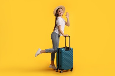 Photo of Woman in straw hat with suitcase on orange background