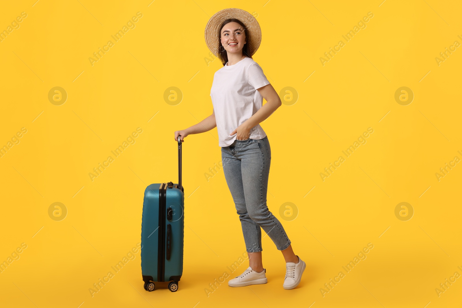 Photo of Woman in straw hat with suitcase on orange background