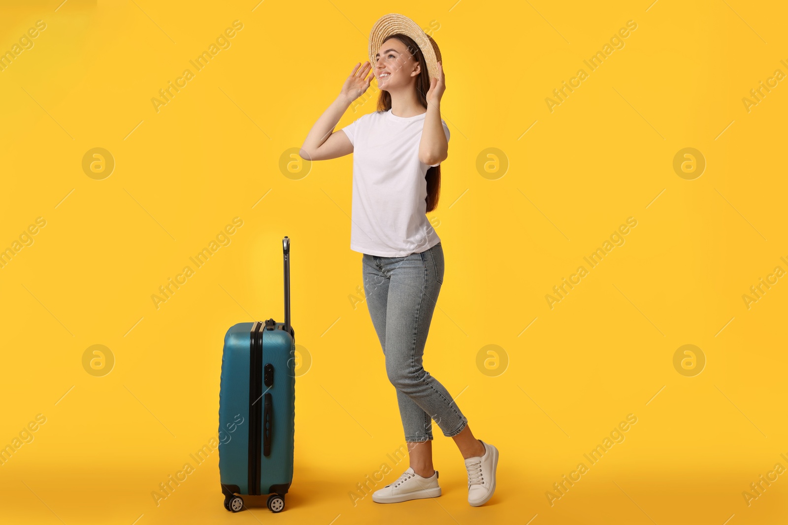 Photo of Woman in straw hat with suitcase on orange background