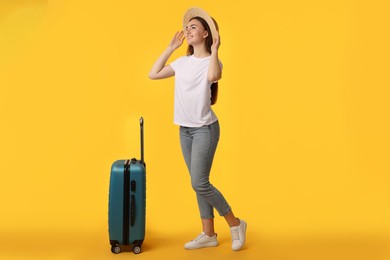 Photo of Woman in straw hat with suitcase on orange background