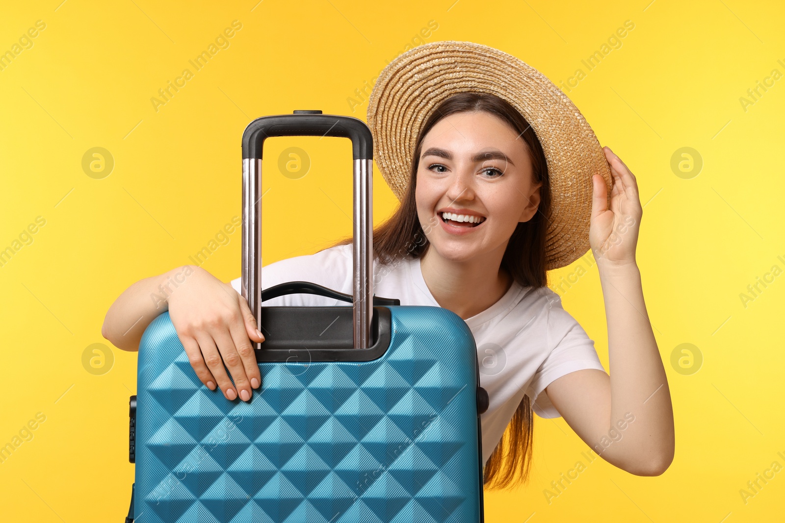 Photo of Woman in straw hat with suitcase on orange background