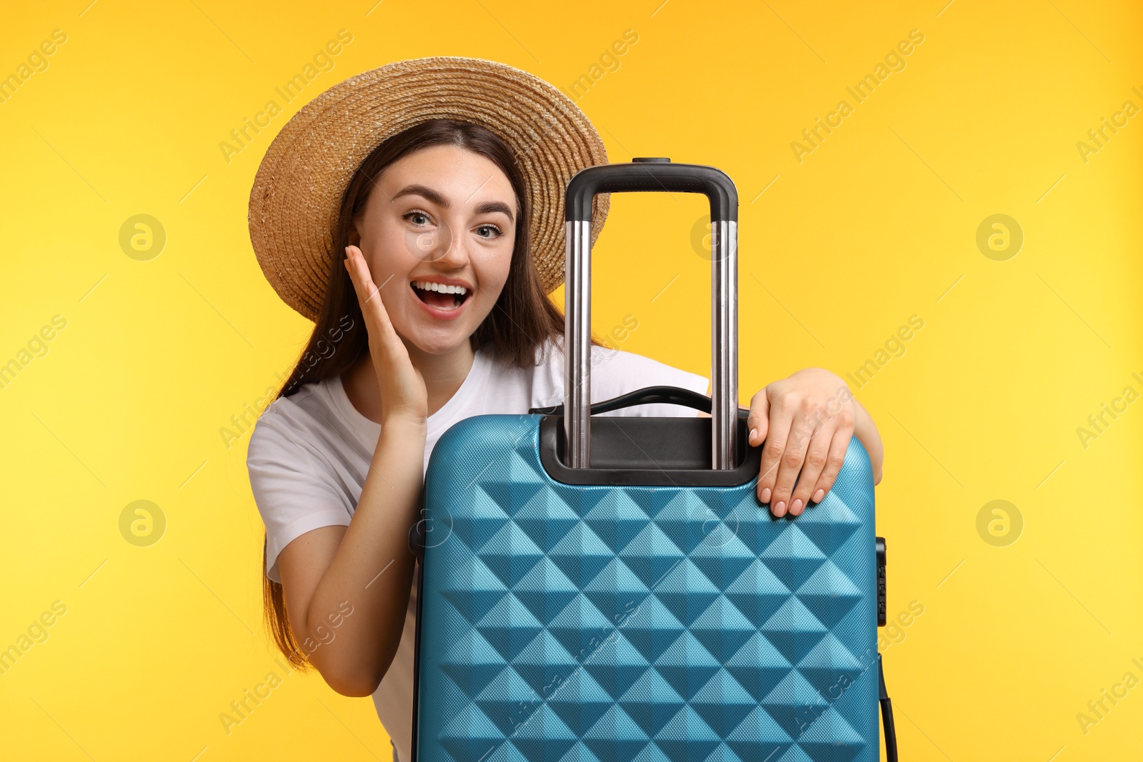 Photo of Woman in straw hat with suitcase on orange background