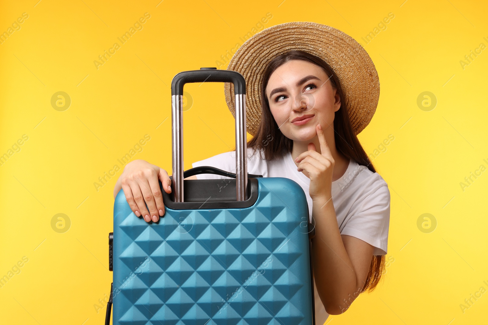 Photo of Woman in straw hat with suitcase on orange background