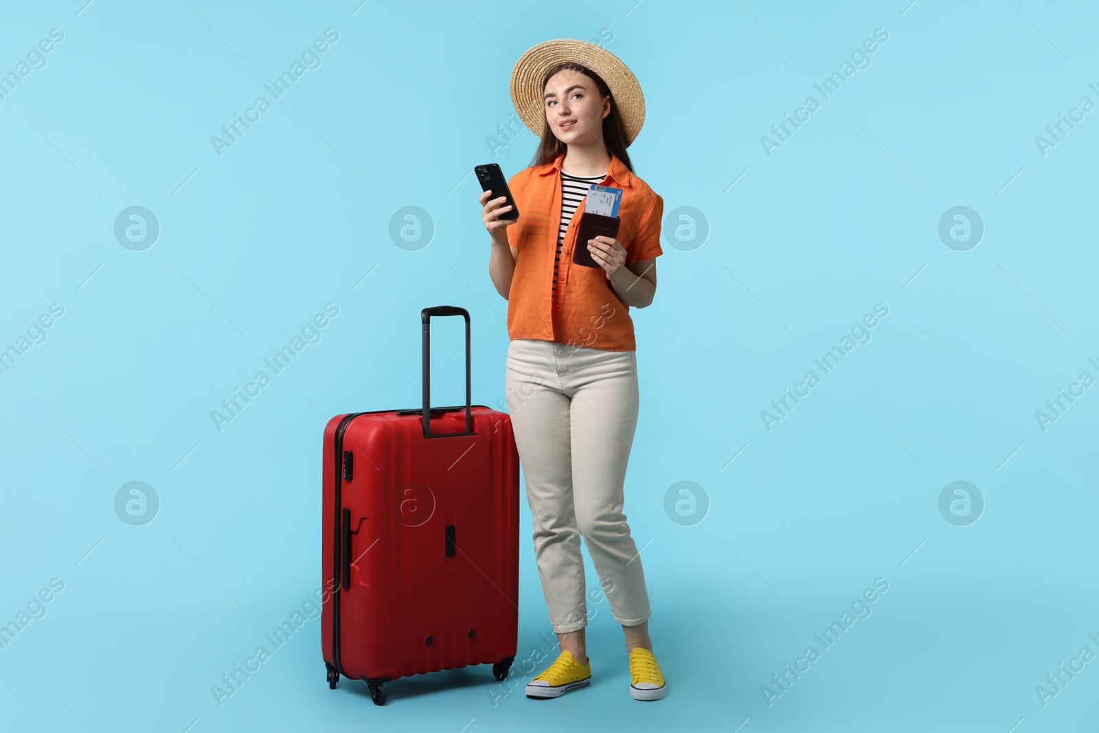 Photo of Woman with ticket, passport, suitcase and smartphone on light blue background