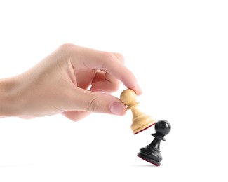 Photo of Man with white pawn knocking over black one on white background, closeup. Competition concept