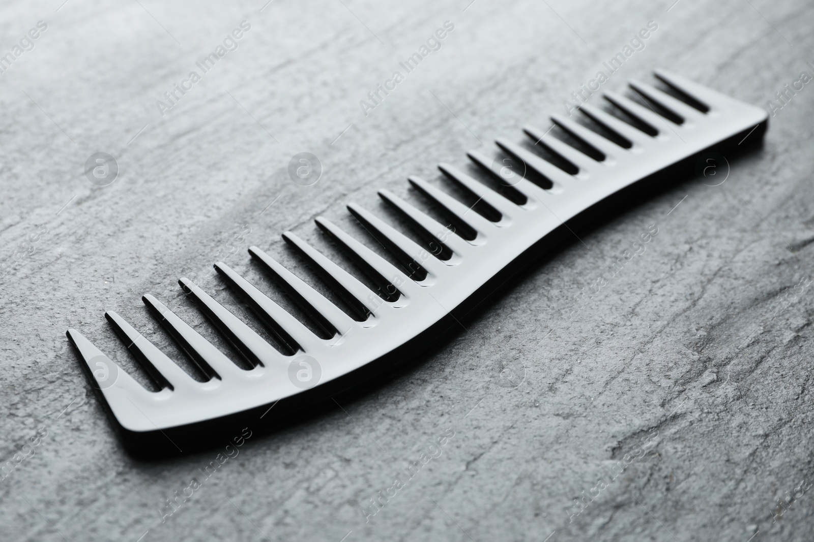 Photo of One plastic hair comb on grey table, closeup