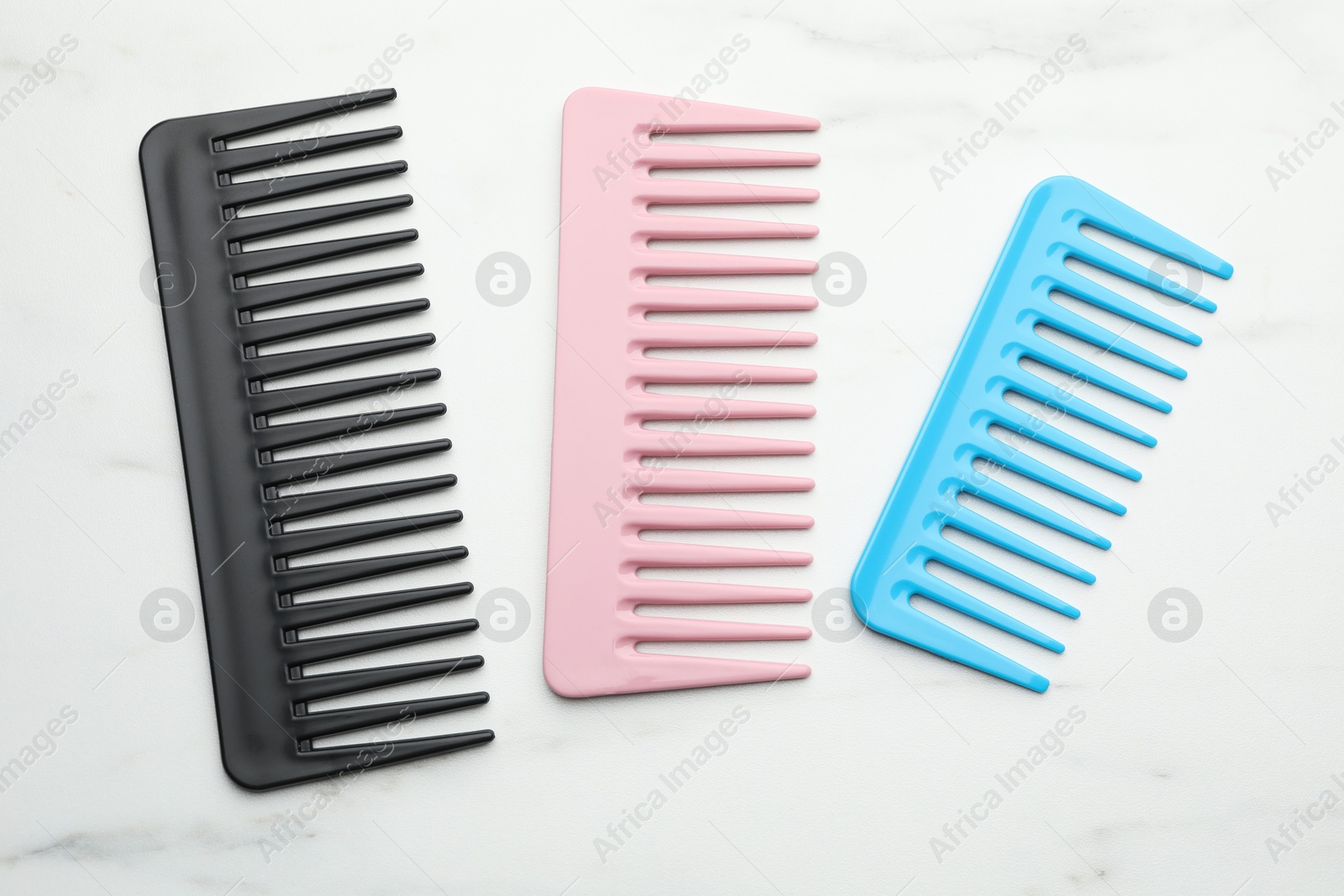 Photo of Different plastic combs on white marble table, top view