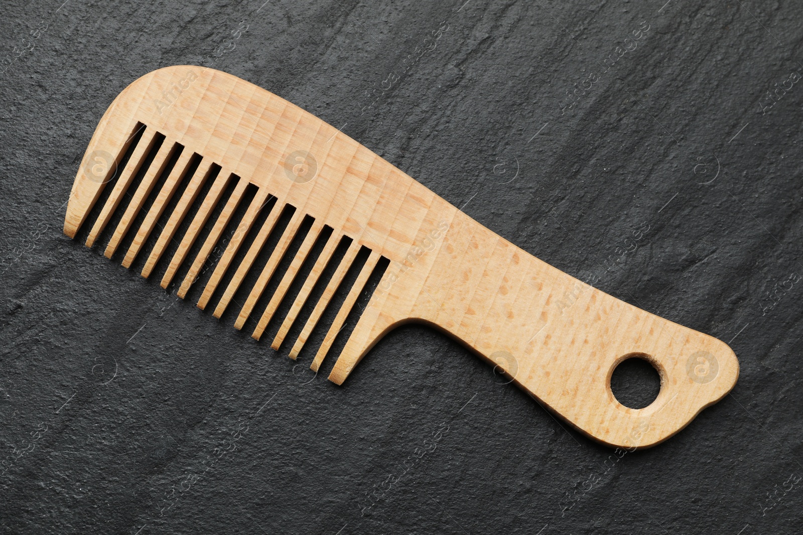 Photo of One wooden hair comb on grey background, top view