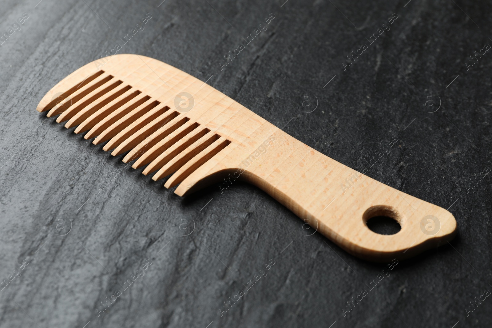 Photo of One wooden hair comb on grey background, closeup