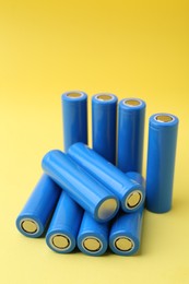 Photo of Many AA cell batteries on yellow background, closeup