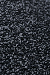 Pile of black plastic granules as background, closeup