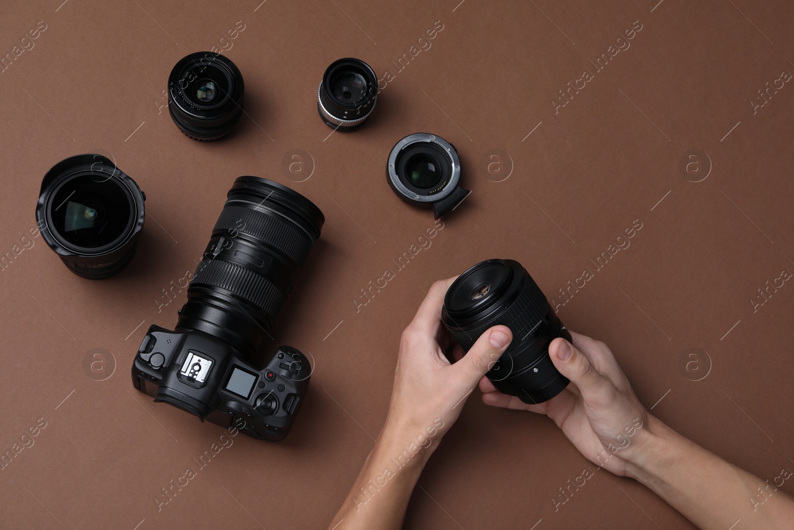 Photo of Photographer with lens and professional camera on brown background, top view