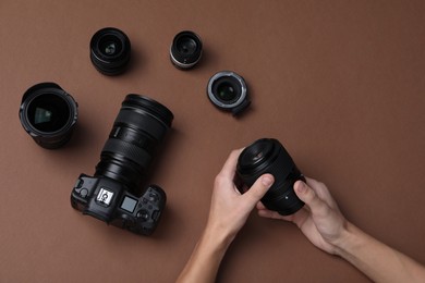 Photo of Photographer with lens and professional camera on brown background, top view