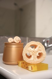 Photo of Loofah sponge and cosmetic products on sink in bathroom