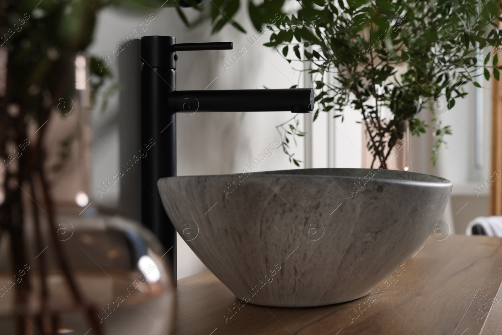 Photo of Eucalyptus branches near vessel sink on bathroom vanity. Interior design