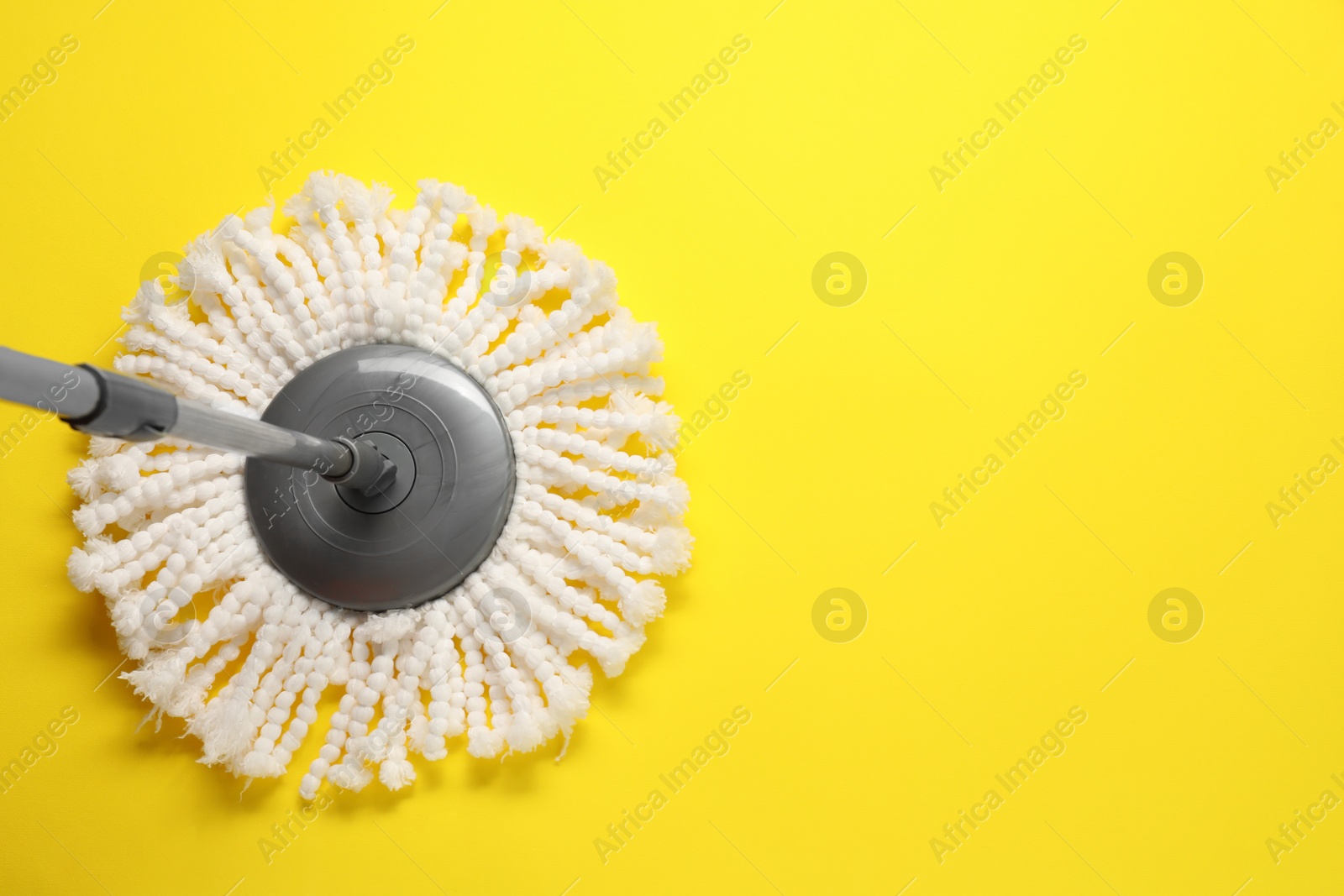 Photo of Mop with metal handle on yellow background, top view. Space for text