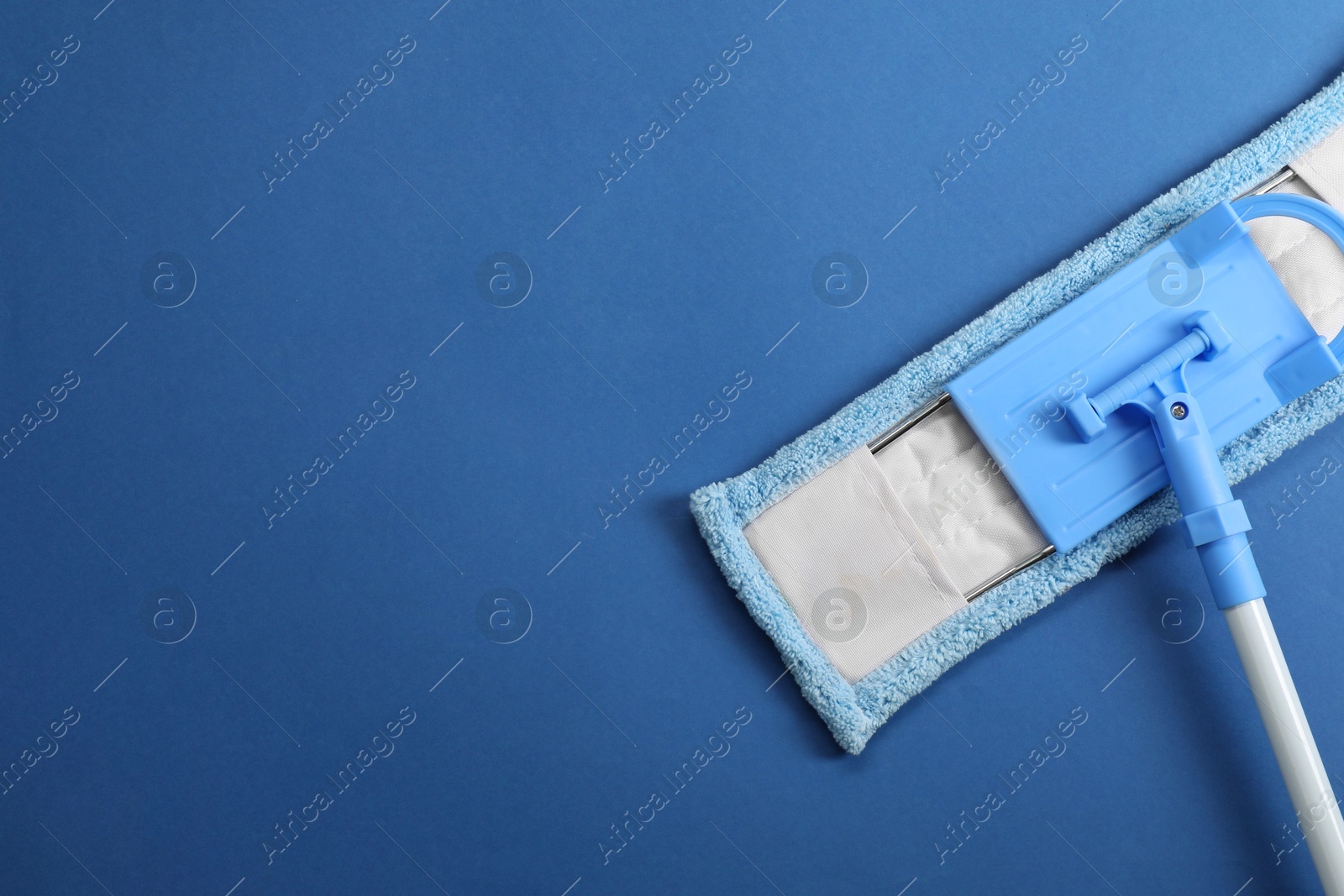 Photo of Mop with plastic handle on blue background, top view. Space for text