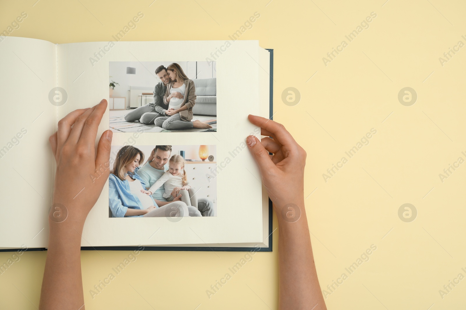 Photo of Woman looking at family photos in photo album on beige background, top view. Space for text