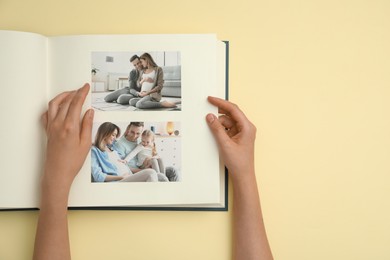 Photo of Woman looking at family photos in photo album on beige background, top view. Space for text