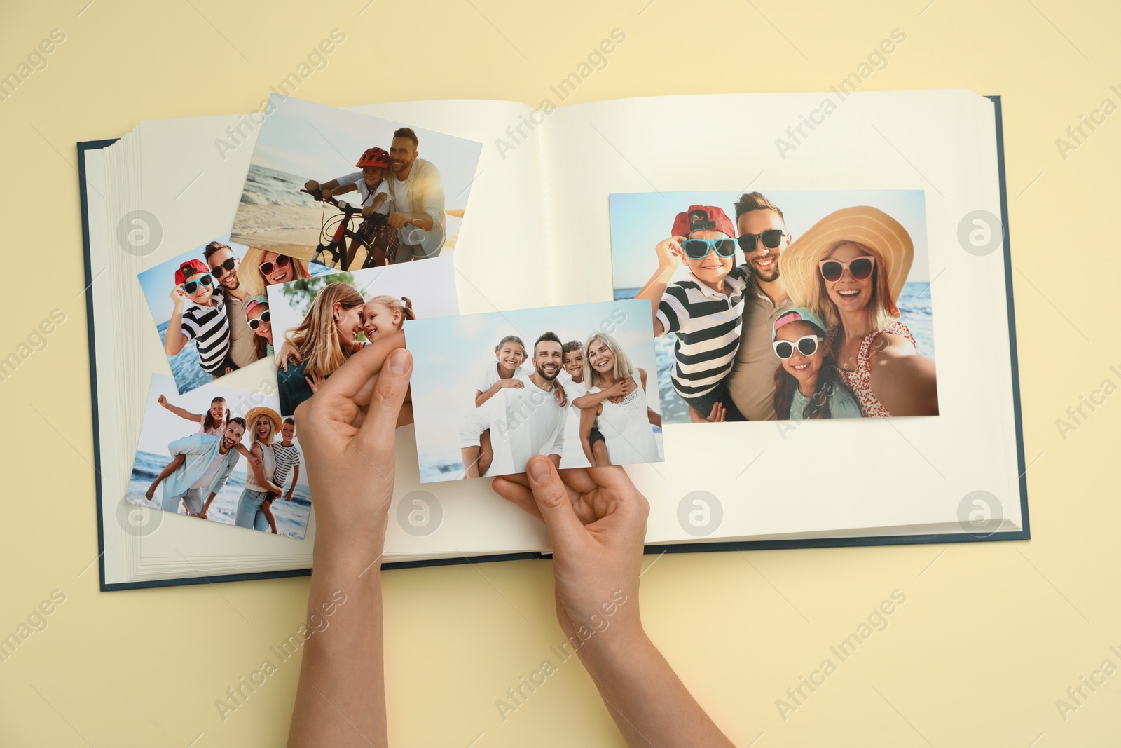 Photo of Woman with open photo album and different photos on beige background, top view