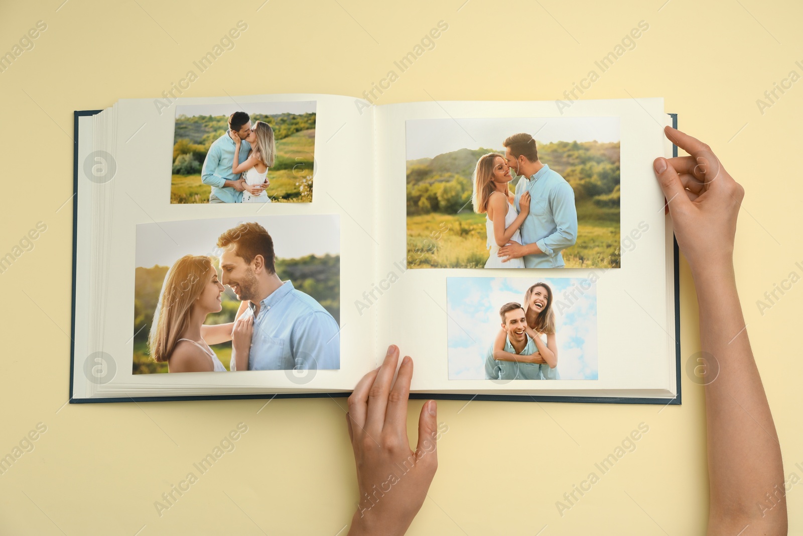 Photo of Woman looking at family photos in photo album on beige background, top view