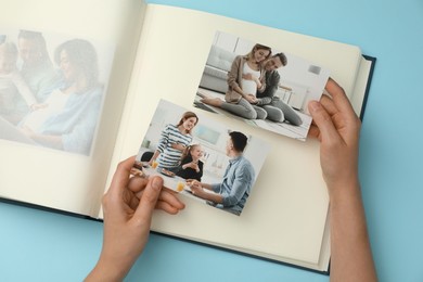 Photo of Woman with open photo album and different photos on light blue background, top view