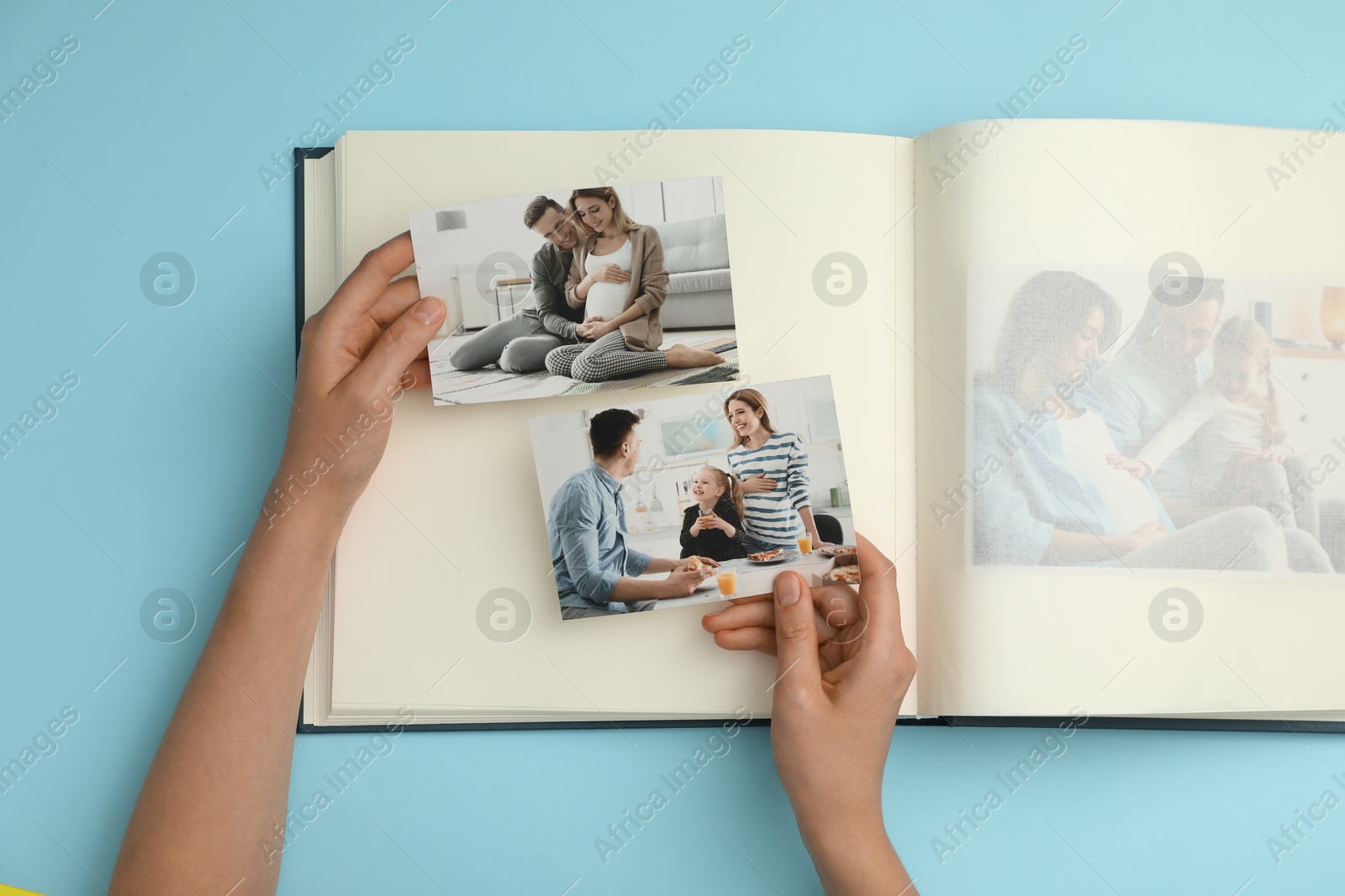 Photo of Woman with open photo album and different photos on light blue background, top view