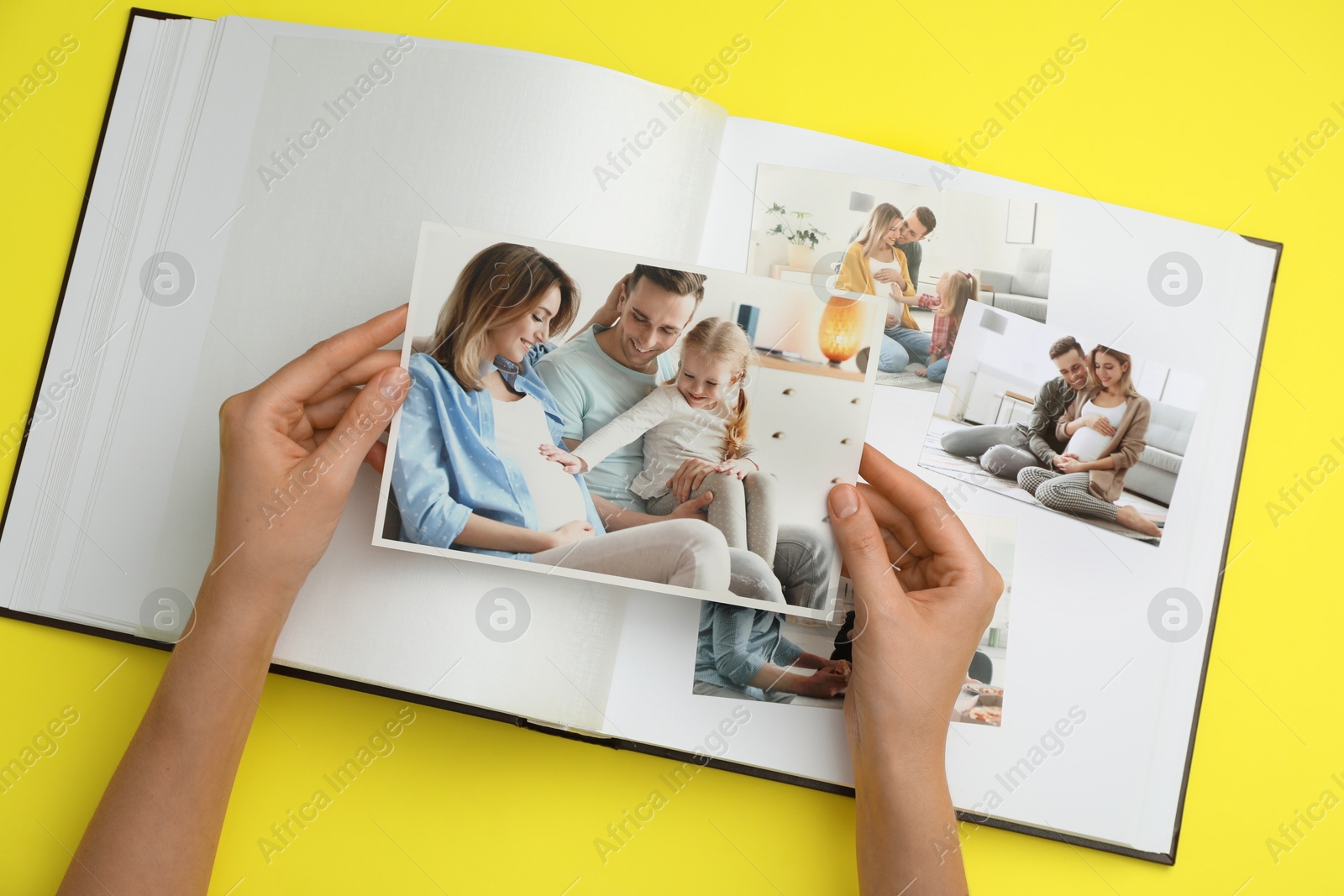 Photo of Woman with open photo album and different photos on yellow background, top view