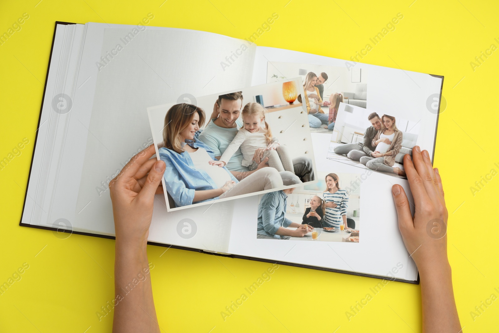 Photo of Woman with open photo album and different photos on yellow background, top view