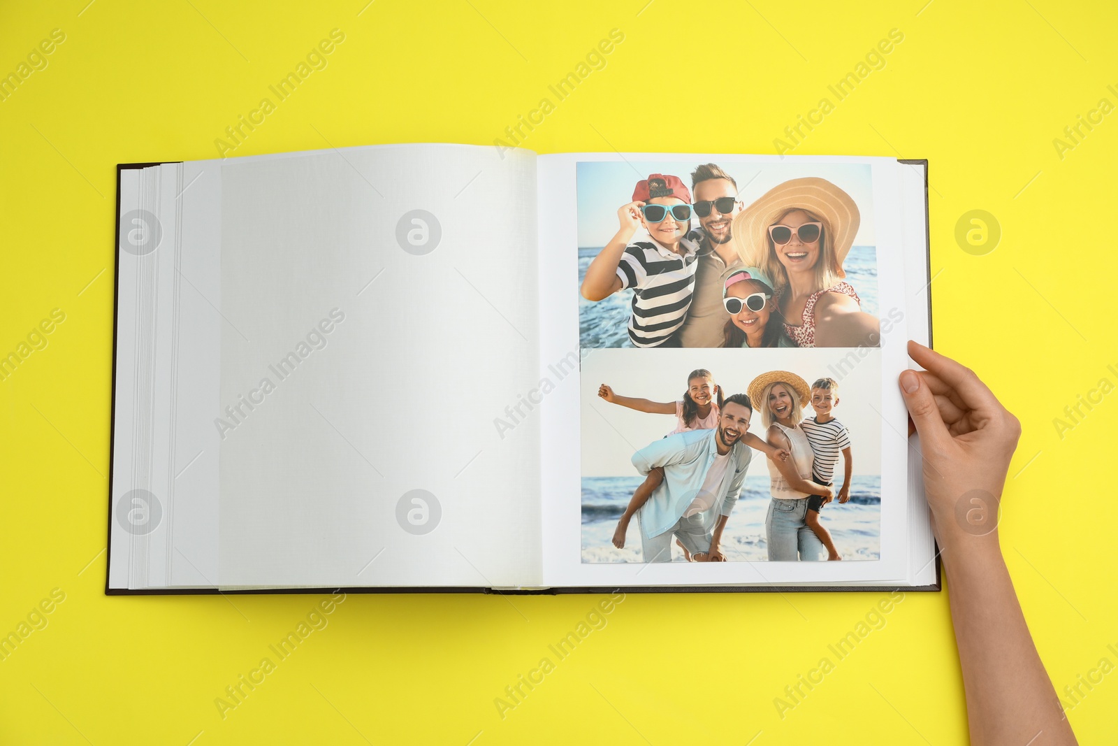 Photo of Woman looking at family photos in photo album on yellow background, top view