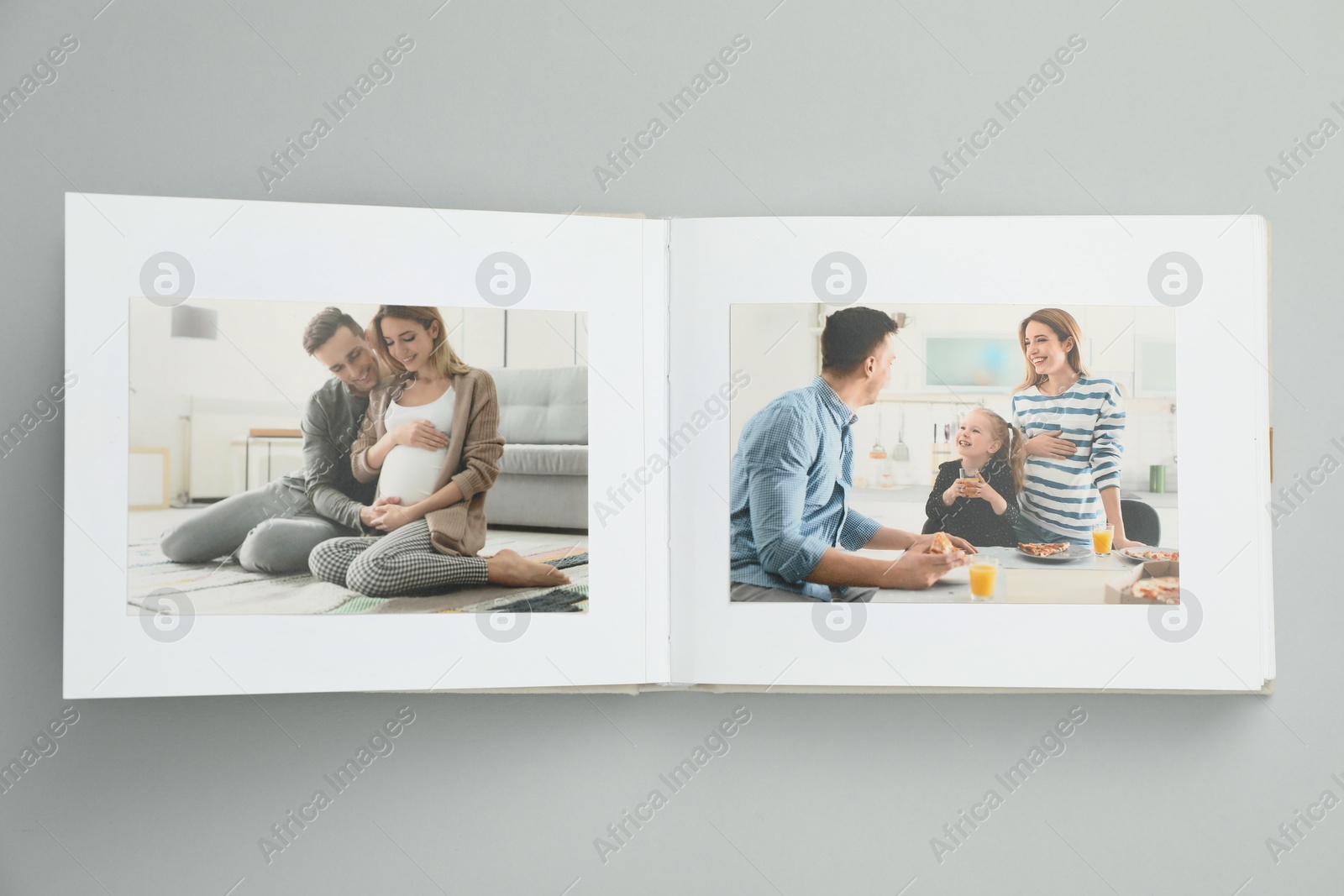 Photo of Open photo album with photos on grey background, top view