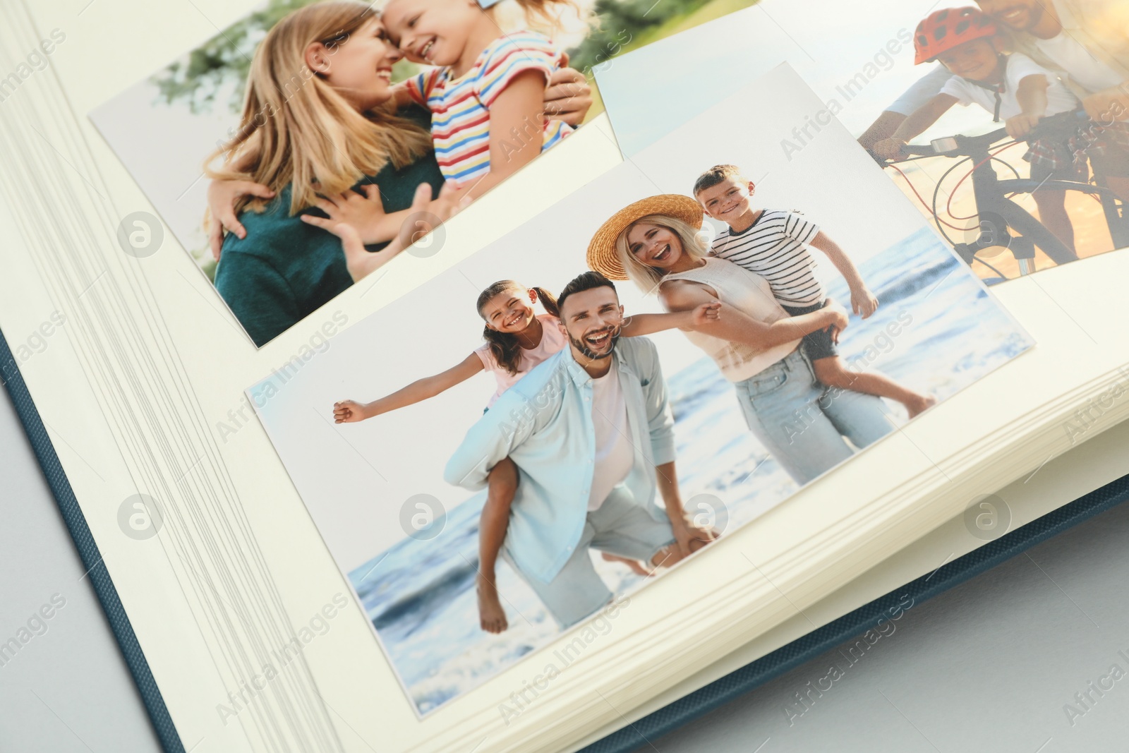 Photo of Open photo album with different photos on grey background, closeup