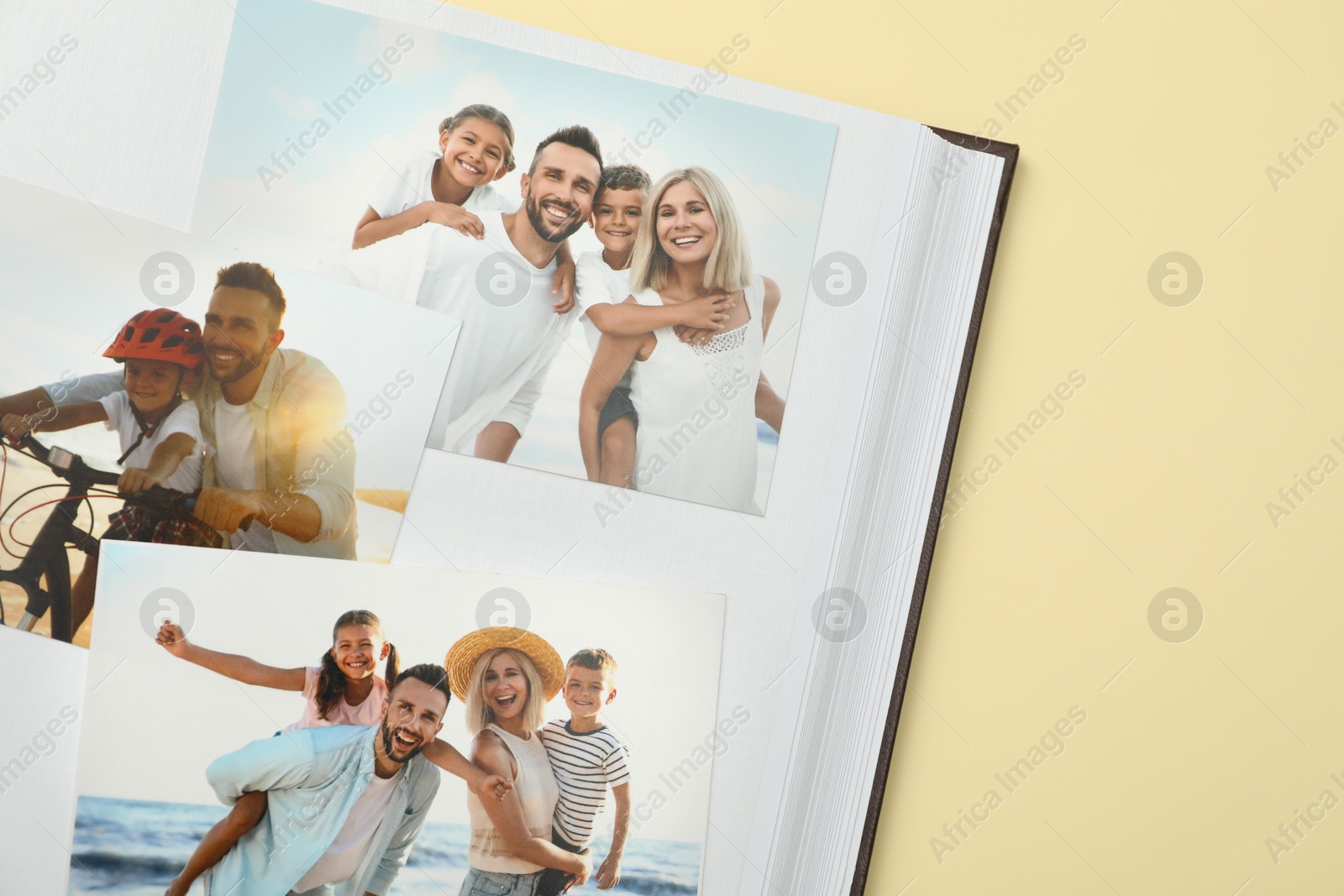 Photo of Open photo album with different photos on beige background, top view